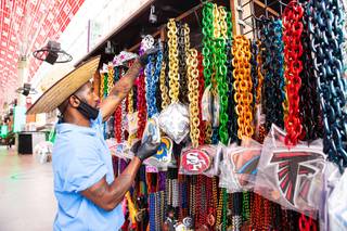 Samuel Laster hangs up souvenir necklaces at the Big Balls kiosk on Fremont Street Experience as it prepares for the reopening of the casinos, Wed., June 3, 2020.