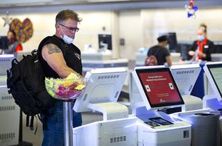 A man uses a self-service kiosk to check in for a flight at McCarran International Airport Thursday, July 2, 2020.