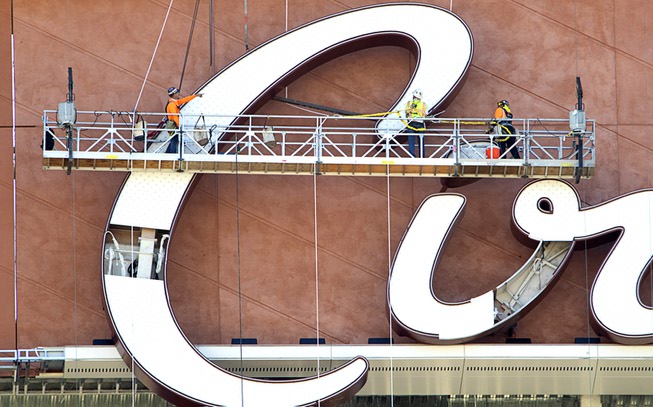 Workers complete the installation of an exterior Circa sign on ...