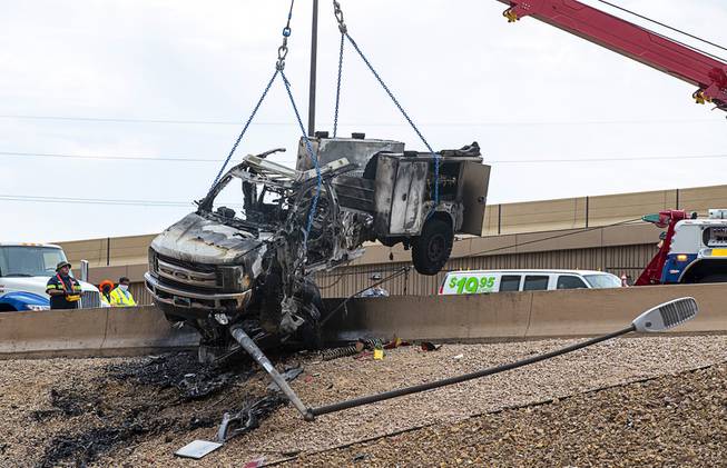 A Big Valley Towing heavy rescue unit lifts a pickup truck off another car after fiery morning accident on the I-15 northbound to U.S. 95 northbound offramp at the Spaghetti Bowl Thursday, Aug. 13, 2020. Three people, including a child, died in the crash. 