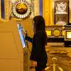 A Caesars Palace employee disinfects a self serve kiosk in the lobby after guests check into their room, Thursday Aug. 13, 2020.