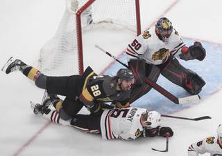 Vegas Golden Knights' William Carrier (28) and Chicago Blackhawks' Connor Murphy (5) battle as Blackhawks goalie Corey Crawford (50) looks for the puck during the third period of an NHL hockey Stanley Cup first-round playoff series, Thursday, Aug. 13, 2020, in Edmonton, Alberta. (Jason Franson/The Canadian Press via AP)