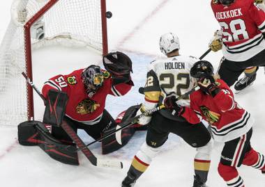 Vegas Golden Knights’ Nick Holden (22) is stopped by Chicago Blackhawks’ goalie Corey Crawford (50) as Blackhawks’ Alexander Nylander (92) defends during first-period NHL Western Conference Stanley Cup playoff hockey action in Edmonton, Alberta, Sunday, Aug. 16, 2020. (Jason Franson/The Canadian Press via AP)