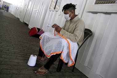 Pedro Henrique wears a face mask as he crochets, which he learned in a weaving workshop at the Solidary Hands shelter for the homeless, in the poor neighborhood of Ceilandia, in Brasilia, Brazil.