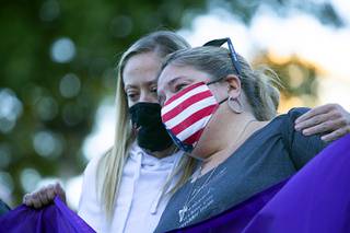 Sarah Lammers of Littleton, Colo, a survivor of the 1999 Columbine shooting, holds Jill Winter of San Diego, an Oct. 1 was shooting survivor, during a 1 October Sunrise Remembrance ceremony at the Clark County Government Center amphitheater Thursday, Oct 1, 2020.