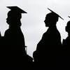 In this May 17, 2018, file photo, new graduates line up before the start of the Bergen Community College commencement at MetLife Stadium in East Rutherford, N.J. Many new college graduates are struggling to find work as their first student loan payments loom on the horizon. Fewer entry-level jobs are available during the pandemic, and unemployment benefits typically aren’t accessible. 