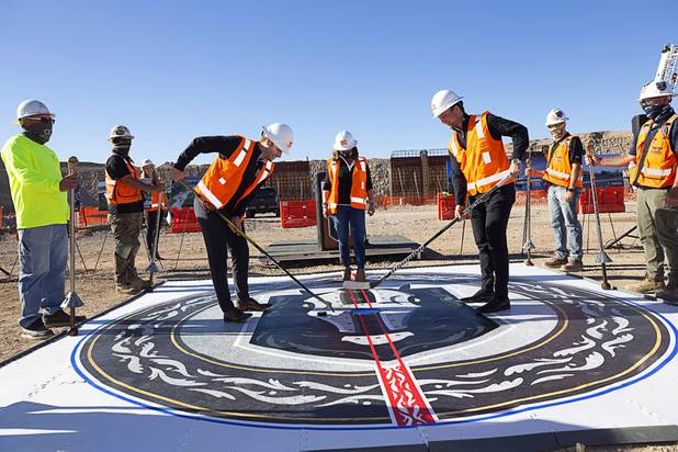 Vegas Golden Knights' Gage Quinney, left, gets control of the puck against teammate Reid Duke in a ceremonial puck drop during the celebration of a construction milestone at the Henderson Events Center construction site Wednesday, Oct. 28, 2020. Henderson Mayor Debra March is at center. The multi-purpose, 6,000-seat indoor events center will be the arena for the Henderson Silver Knights.