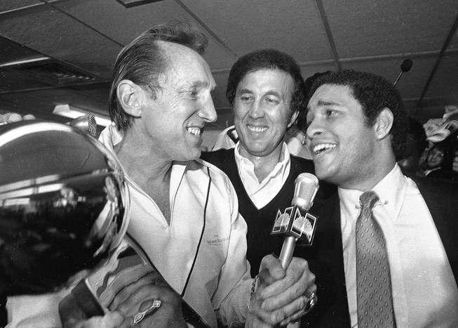 In this Jan. 25, 1981, file photo, Oakland Raiders managing general partner Al Davis, left, talks with sportscaster Bryant Gumbel, right, after receiving the Super Bowl XV trophy as Raiders head coach Tom Flores, center, looks on in New Orleans. When Flores won his first Super Bowl as head coach of the Raiders 35 years ago, the impact of being the first Hispanic coach to reach those heights did not hit until well after the game. 