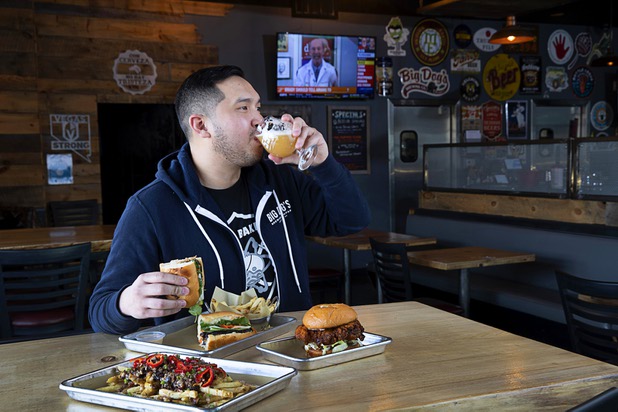 Van-Alan Nguyen, owner of 595 Craft and Kitchen and Art District Kitchen, drinks a glass of Beachwood Brewing's "Khakis & Car Keys?" IPA in 595 Craft at Rainbow Boulevard and Tropicana Avenue Wednesday, Nov. 11, 2020. Also pictured are Hangover Fries, Pork Belly Banh Mi and a Nashville-style Hot Chicken Sandwich.