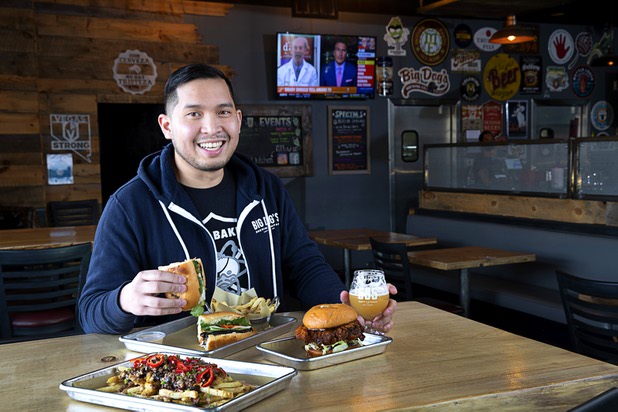 Van-Alan Nguyen, owner of 595 Craft and Kitchen and Art District Kitchen, poses with a Pork Belly Banh Mi and a glass of Beachwood Brewing's "Khakis & Car Keys?" IPA in 595 Craft at Rainbow Boulevard and Tropicana Avenue Wednesday, Nov. 11, 2020. Also pictured are Hangover Fries and a Nashville-style Hot Chicken Sandwich.