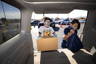 Jude Romero, 11, left, and Liam Jones, 10, load a food box and a frozen turkey into a vehicle during a Thanksgiving food distribution event in the parking lot of the Desert Breeze Community Center Saturday, Nov. 21, 2020. The event was a partnership between Clark County Commissioner Justin Jones, Three Square and Catholic Charities of Southern Nevada.