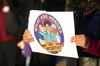 Surgical technician Erika Watanabe, right, holds a sign as healthcare workers as they protest working conditions during 