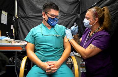Dr. Myron Kung, a critical care physician, gets the COVID-19 vaccine from registered nurse Darlene Roberts as the vaccination begins for health care workers at the VA Southern Nevada Healthcare System in North Las Vegas Wednesday, Dec. 16,&nbsp;2020. 