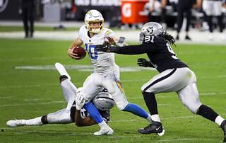 Las Vegas Raider cornerback Daryl Worley (36) and defensive tackle Kendal Vickers (91) put pressure on Los Angeles Chargers quarterback Justin Herbert (10) during the second half of a game against the Los Angeles Chargers at Allegiant Stadium Thursday, Dec. 17, 2020.