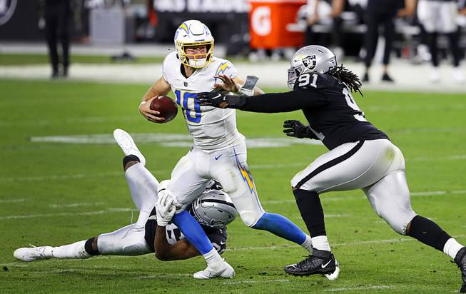 Las Vegas Raider cornerback Daryl Worley (36) and defensive tackle Kendal Vickers (91) put pressure on Los Angeles Chargers quarterback Justin Herbert (10) during the second half of a game against the Los Angeles Chargers at Allegiant Stadium Thursday, Dec. 17, 2020.