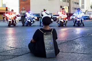 A protester sits on street while officers close off Las Vegas Blvd at St. Louis Ave. for a small gathering Wednesday, June 3, 2020, in Las Vegas, during the sixth day of demonstrations over the death of George Floyd, who died May 25 after he was pinned at the neck by a Minneapolis police officer. YASMINA CHAVEZ