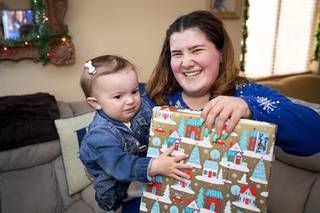 Yvonne Wallace, 18, holds a present with her daughter Rose, 1, after a Hope For Prisoners gift delivery Saturday, Dec. 19, 2020.