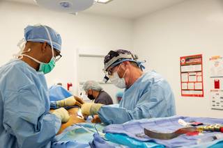 From left, Surgical Technologist Bryan Bernard assists Dr. Lane Smith, of Smith Plastic Surgery, during a breast augmentation at the Surgical Institute of Las Vegas Monday, Dec. 21, 2020. Dr. Michael Crawley, Anesthesiologists, is seen in the background.