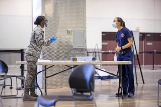 Nevada National Guard Airman Jada Wansley, checks in Jasmine Ghazinour, a Clark County Fire captain, at a pre-screening table during COVID-19 vaccinations at Cashman Field Thursday, Jan. 14, 2021. The vaccinations to public safety workers are part of a pilot program for a larger mass vaccination effort, officials said.