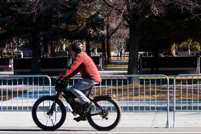 A man rides his bicycle by near barricades set up by authorities at the Nevada State Capitol complex for a rumored pro-Trump demonstration that didn't happen Sunday, Jan. 17, 2021. 
