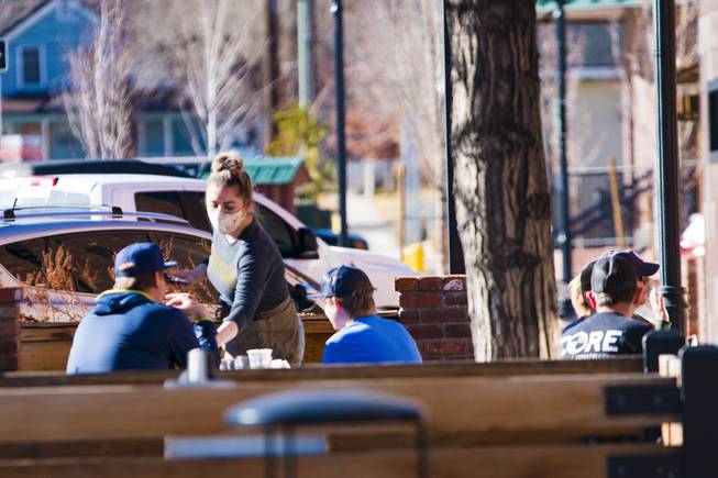 A waitress serves lunch to diners at The Union's outdoor patio in Carson City, Nev. Monday, Jan. 18, 2021. The eatery, taphouse and coffee shop is located near the Nevada Capitol. 