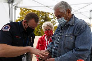 Ron Shutter, 81, and his partner Elizabeth Harvey, 81, get help filling out an online form by Firefighter Josh Barrone   while waiting in line for a COVID-19 vaccine at the Elaine K. Smith Center in Boulder City, Monday, Feb. 1, 2021.