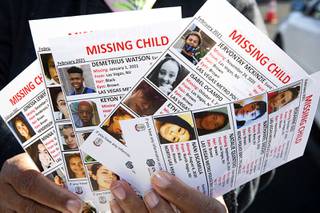 Volunteer Tamia Dow displays missing child flyers at a drive-thru dispatch center during 