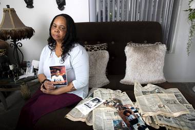Debra Simms holds a photo of her son in her apartment Saturday, Feb. 13, 2021. Xavier Danaurd Crockett Simms, 15, and friend Jason Moore were killed in 1996. Twenty-five years after the killings, a man has confessed to the murders, police said. At right are more photos of her son and newspapers from 1996 reporting on the murders.