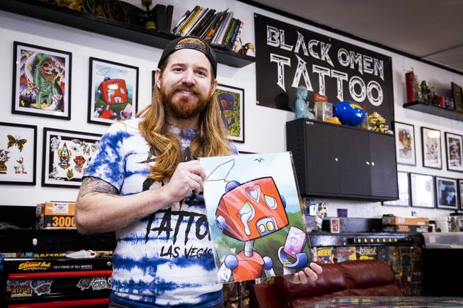Caleb Cashew, owner of Black Omen Tattoo, is shown next ...