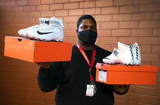 Thomas Smith, assistant principal in charge of athletics at Valley High School, poses with new Nike cleats, donated by the Las Vegas Raiders, at the school Thursday, Feb. 25, 2021.