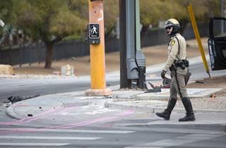 A Metro Police officer walks by an accident scene at the intersection of Las Vegas Boulevard North and Washington Avenue Saturday, March 13, 2021. One of the two vehicles involved in the accident left the roadway and hit a pedestrian, injuring him critically, police said.