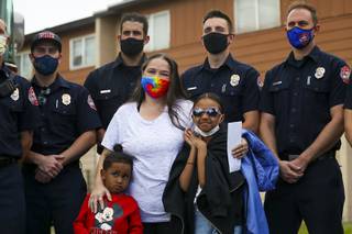 Michael Robinson, 4, Karlycia Osorio, 8, and their grandmother Lynn Armstrong pose for a photo with the crew of firefighters that saved them from their apartment fire in North Las Vegas, Tuesday, March 23, 2021. Jordan Spears, top right, had to ignore safety protocols when he entered the burning home in order to rescue 5-year-old Maleyah Robinson, who is recovering from injuries at the hospital.