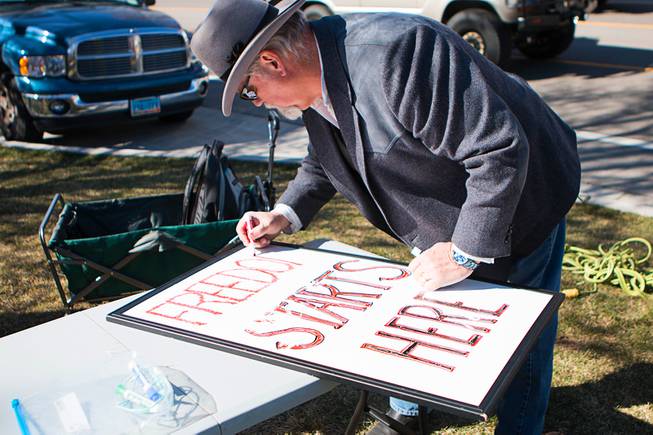 A man works on a sign during a pro-gun rally at the Nevada State Capitol complex in Carson City Saturday, March 27, 2021. The protesters are opposed gun control legislation, including AB 286, which would ban ghost guns, or firearms without serial numbers, which are often built at home. About 100 people attended the rally.