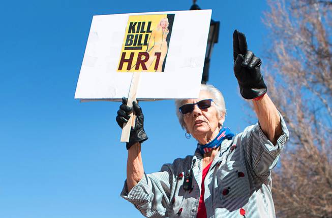 A woman holds up a sign during a pro-gun rally at the Nevada State Capitol complex in Carson City Saturday, March 27, 2021. The protesters are opposed gun control legislation, including AB 286, which would ban ghost guns, or firearms without serial numbers, which are often built at home. About 100 people attended the rally.