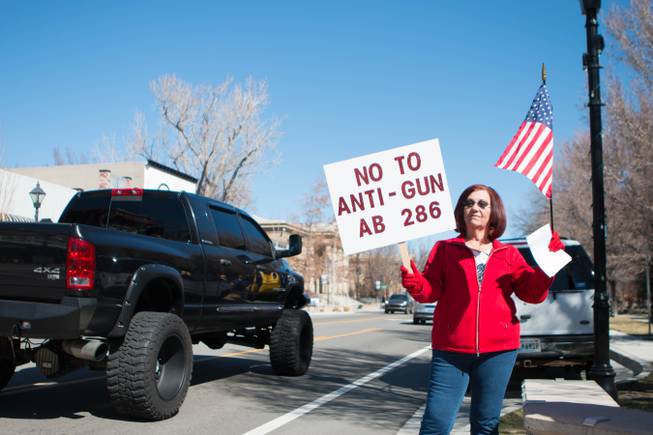 An unidentified woman flashes a protest sign at the Nevada State Capitol complex Saturday, March 27, 2021. The protest of Assembly Bill 286, which would ban “ghost guns,” attracted about 100 participants. 
