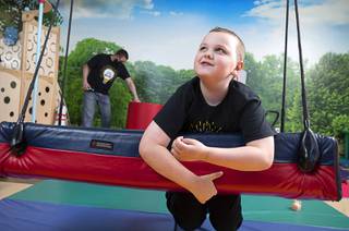 Caleb Maves, 8, plays on a swing in Caesars Park at Touro University Center for Autism & Developmental Disabilities in Henderson, Thursday, April 8, 2021. His father Kevin Maves is background left.