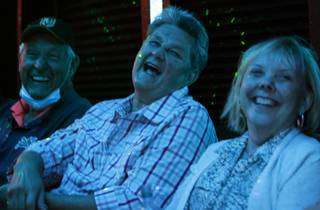 Guests, from left, Jim Shulman, Vicki Shulman, and Donna West, laugh at a joke during a Smiley Joe Wiley comedy party bus Wednesday, April 14, 2021.