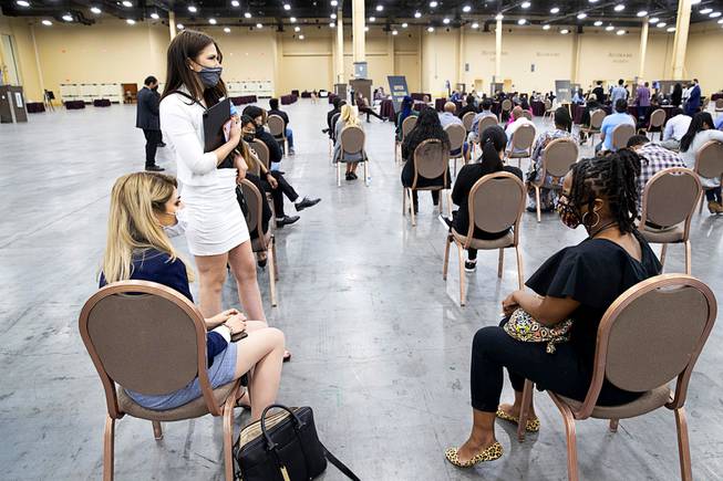 Sabrina Ellison, bottom left, Szabina Szeplaki, standing and Charis Jimmons chat as they wait for job offers during an MGM Resorts hiring fair at the Mandalay Bay Convention Center Tuesday, May 4, 2021. The women had become acquainted during the interview process.