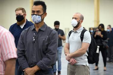 Poker dealer Nick Diana, right, waits in line for a COVID-19 test after getting a job offer during an MGM Resorts hiring fair at the Mandalay Bay Convention Center Tuesday, May 4, 2021.