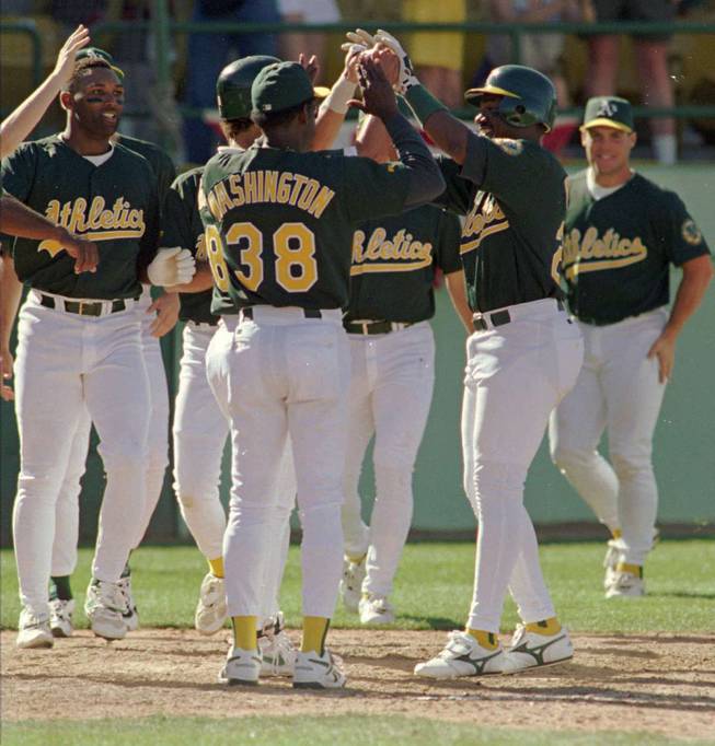 The Oakland Athletics dugout, including coach Ron Washington (38) empties to greet Geronimo Berroa, second right, after his game-winning home run April 7, 1996, at Cashman Field.