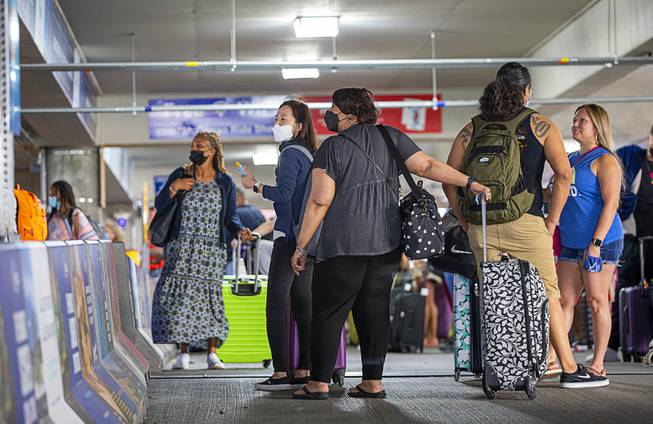 People wait at the rideshare pickup area in the Terminal One parking garage at McCarran International Airport Thursday, May 20, 2021.