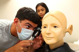 Asher Gordon, a Silverado High School graduate, looks into an ear during a UNLV Nurse Camp for high school students at UNLV School of Medicine's Clinical Simulation Center Wednesday July 14, 2021. UNLV nursing student Kamryn Cruz watches in the background.