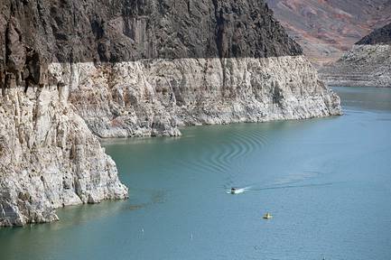 A boater on Lake Mead travels by the bathtub ring near Hoover Dam Thursday, July 15, 2021.