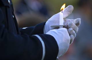 A Nevada Highway Patrol trooper holds a candle during a vigil for NHP Trooper Micah May at Police Memorial Park Tuesday, Aug. 3, 2021. May died Thursday, July 29 after being struck by a car during a pursuit on I-15 July 27.