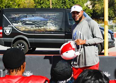 Valley High School football coach Quincy Burts shows players one of their new helmets, donated by the Raiders, during practice Monday, Aug. 9, 2021, at the school. The Raiders are donating 45 helmets specifically designed for the school’s football program.