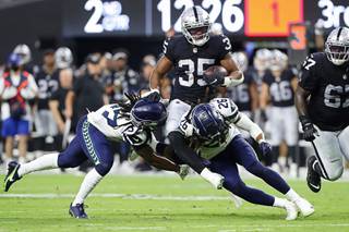 Seattle Seahawks safety Joshua Moon (37) and Seattle Seahawks defensive back Ryan Neal (26) tackle Las Vegas Raiders running back B.J. Emmons during the first half of an NFL preseason football game Saturday, Aug. 14, 2021, in Las Vegas.