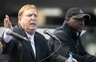 Las Vegas Raiders owner Mark Davis, left, responds to a question during a news conference at Allegiant Stadium Tuesday, Aug. 17, 2021. Jerome Pickett, senior vice president of sports & entertainment for CLEAR, listens at right. Davis and other officials took questions about the Raiders new policy on vaccination requirements for fans at home games.