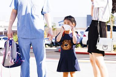 Elena Choi, 5, puts on her mask as she starts kindergarten during the first day of school Aug. 9, 2021, at Hannah Marie Brown Elementary School in Henderson. 