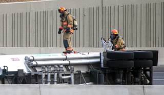 Firefighters work at the scene of an overturned gasoline tanker truck after an early morning accident on U.S. 95 northbound by Valley View Boulevard Wednesday, Sept. 1, 2021. The accident closed the highway in both directions.