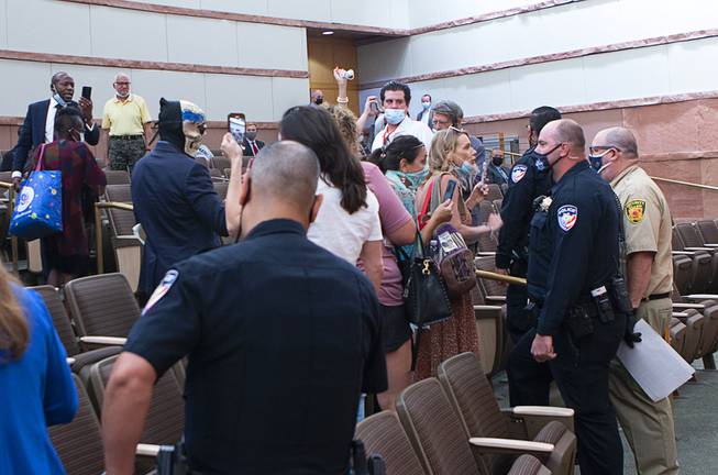 People confront police and security officers over an indoor face mask mandate during a commission meeting at the Clark County Government Center Tuesday, Sept. 21, 2021.